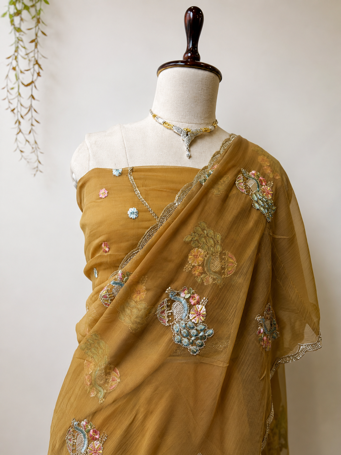 Golden mustard embroidered designer saree on mannequin with floral detailing and elegant border.
