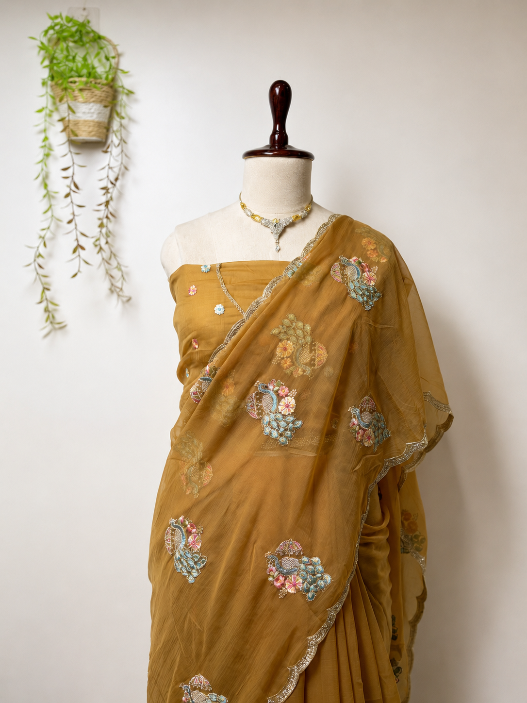 Golden mustard embroidered designer saree on mannequin with floral detailing and elegant border.
