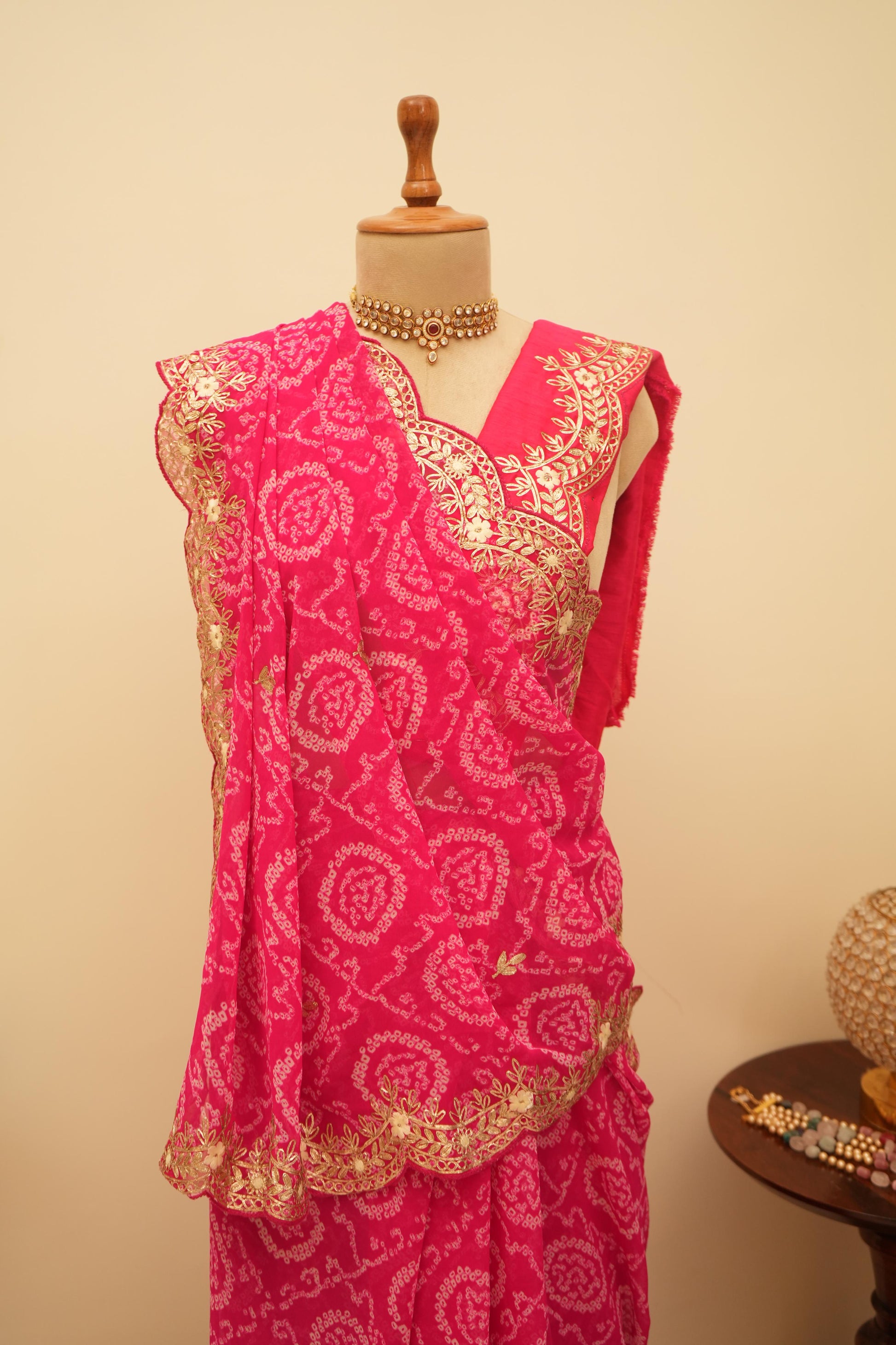 This jaipuri bandhani saree in rani color with traditional patterns and embroidery work border is an ideal bhanej saree for festive occasions.