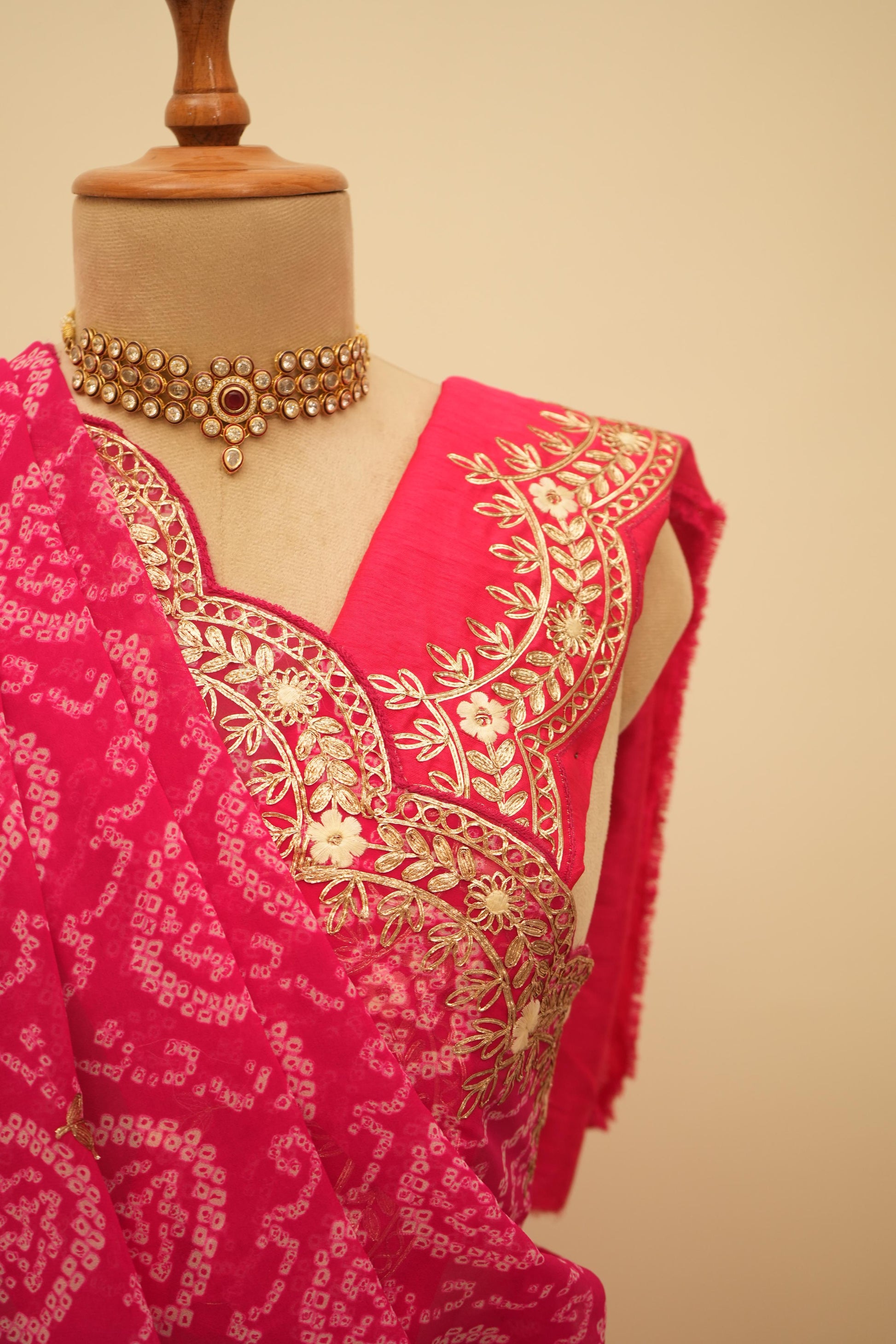 This jaipuri bandhani saree in rani color with traditional patterns and embroidery work border is an ideal bhanej saree for festive occasions.